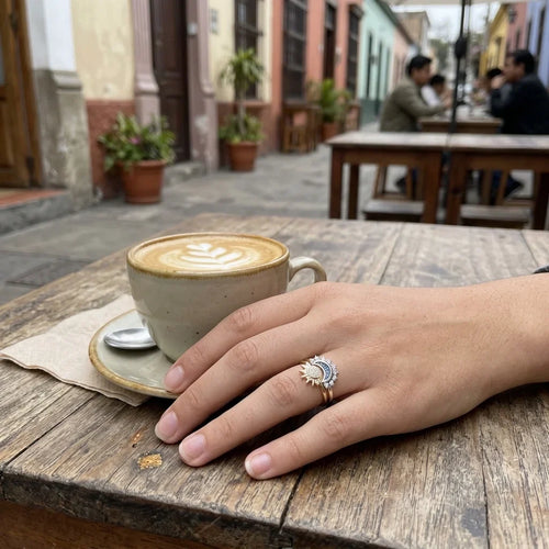 Mano con los anillos sol y luna en una cafetería